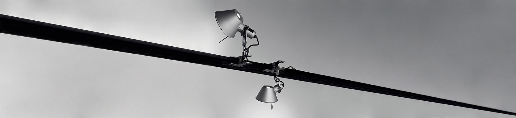 Die Artemide Tolomeo Pinza ist eine flexibel einsetzbare Klemmleuchte für zoniertes Lese- oder Arbeitslicht und basiert auf der wohl bekanntesten Schreibtischleuchte Tolomeo Tavolo, die der Feder von Michele de Lucchi entstammt. Bereits 1987 wurde dieser Designklassiker zeitgemäßer Schreibtischbeleuchtung auf den Markt gebracht. Seit 1995 sorgt die Tolomeo Pinza für optimal zoniertes Lese- oder Arbeitslicht neben Sofa und Sessel, am Bücherregal montiert oder in der Küche als zusätzliche Arbeitsplattenbeleuchtung sowie vielleicht auch über dem Bett als Leselicht. Die Leuchtenserie Tolomeo überzeugt mit ihren technischen Eigenschaften und dem komfortabel ausrichtbaren sowie blendfreien Licht. Tolomeo steht für erstklassige Verarbeitung, maximale Flexibilität, beste Lichtqualität und einen enormen Einsatzradius. Dank dieser hervorragenden Eigenschaften und dem zeitlosen Design wurde die Tolomeo zu der vielleicht weltweit verbreitetsten Leuchte im Arbeitsplatzbereich überhaupt und fungiert bereits als Sinnbild für die italienische Designleuchtenfirma Artemide. Michele de Lucchi wurde für diese Leuchte mit internationalen Designpreisen überhäuft und die immer noch andauernde Erfolgsgeschichte der Tolomeo macht dieses Meisterstück unweigerlich zum Lebenswerk des Stardesigners. Das beeindruckende Portfolio der Tolomeo Familie erstreckt sich von der klassischen Schreibtischleuchte über Stehleuchten, Wandleuchten bis hin zu Decken- oder Pendelleuchten und wartet mit verschiedensten Oberflächen und Werkstoffen auf.